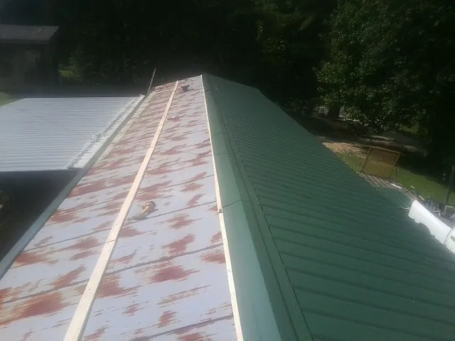 Old rusted panels beside newly installed green metal roofing — Wind Damage Roof Repair by Roofing Brothers in Miltona