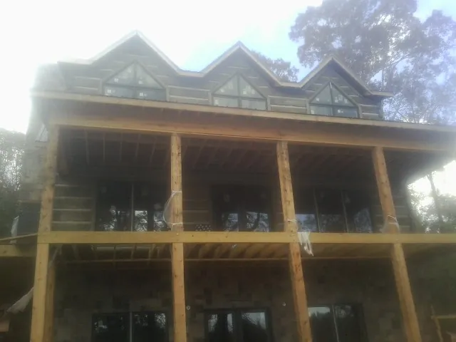 Dormers and porch framing on a large log home under construction — Roof Coating work by our crew in Miltona