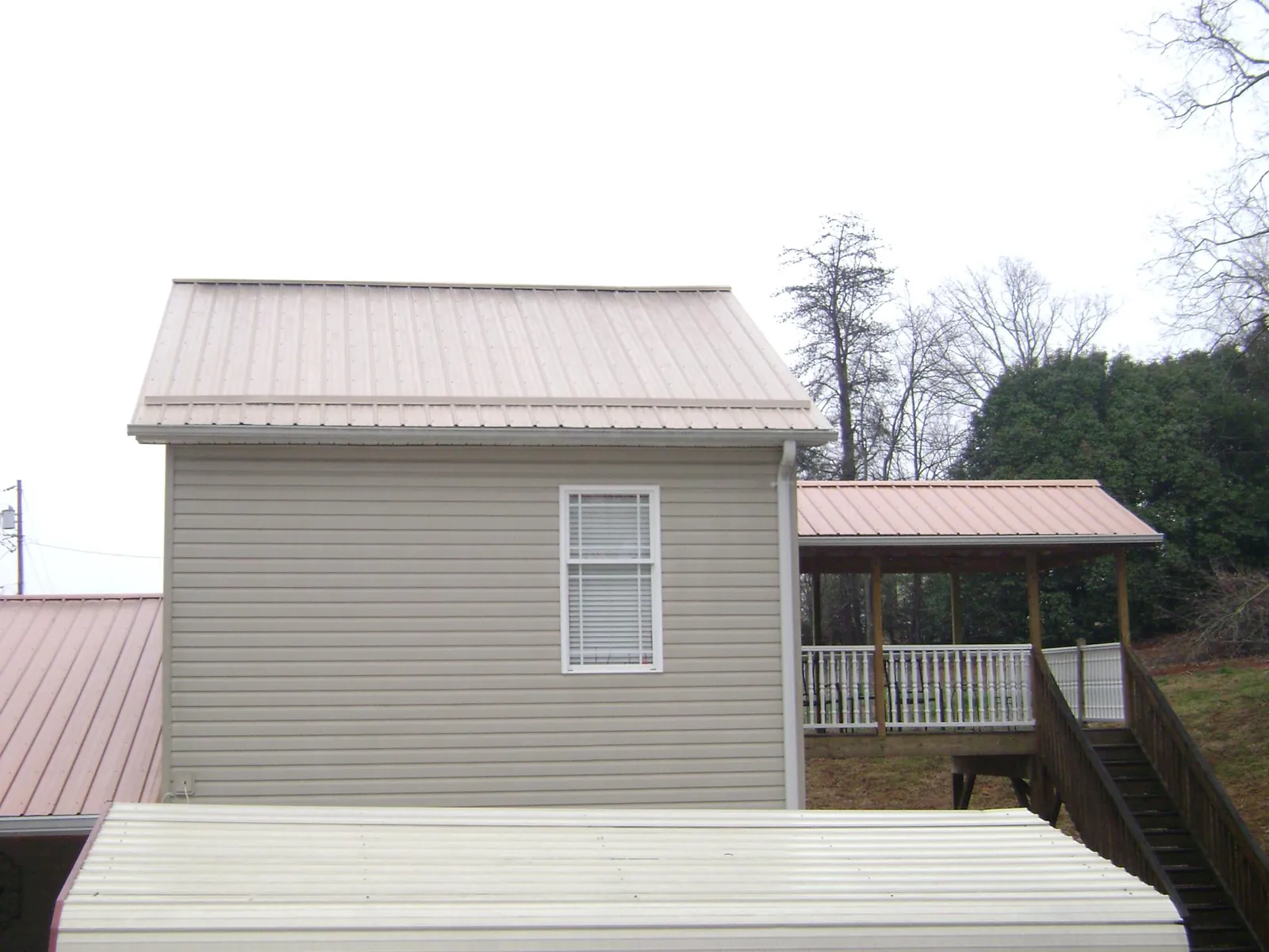 Tan metal roofs on a two story addition and attached porch, from a Roof Replacement job in Miltona