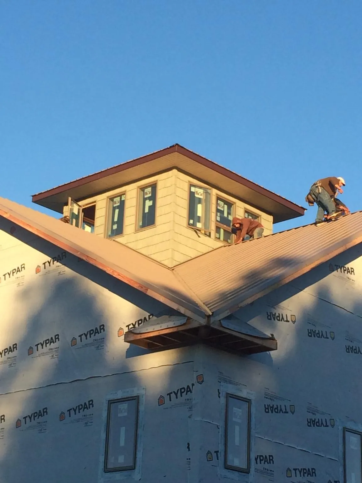 Roofers working around a rooftop cupola on a new metal roof at sunset — Roof Waterproofing in Miltona by Roofing Brothers